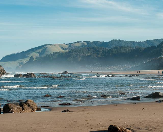 people walk along the water at the beach in Lincoln City, Oregon