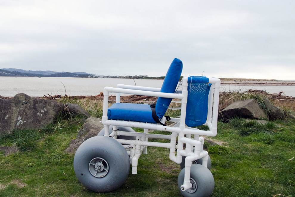 a beach wheelchair on a patch of grass overlooking the water