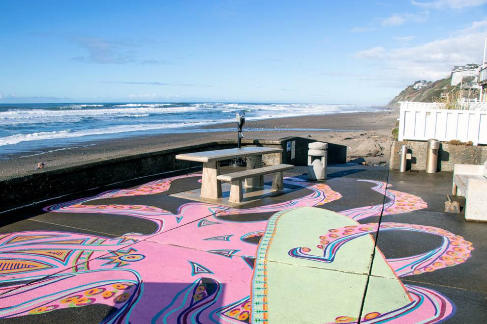 a paved platform with a mural of a pink octopus and picnic table offer wheelchair access to the beach
