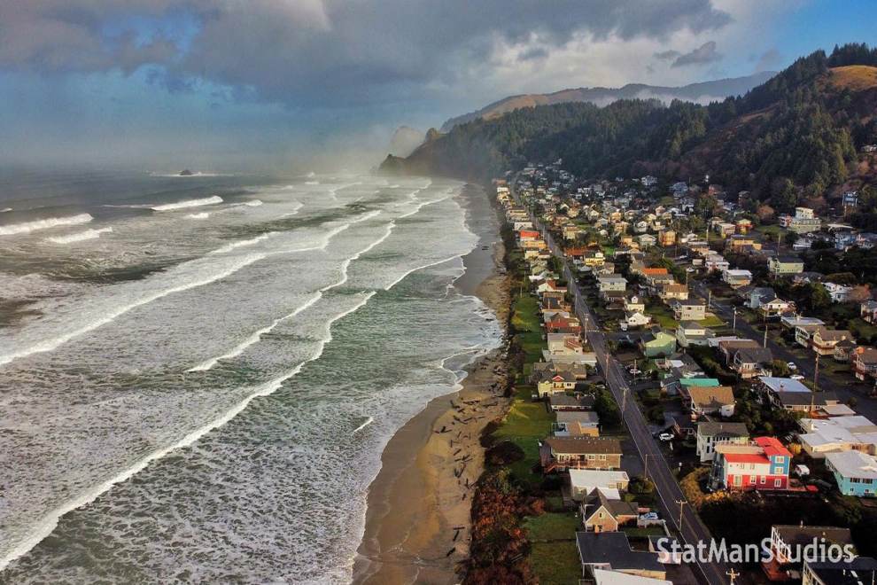 waves rolling into a beach with a neighborhood nearby during King Tides