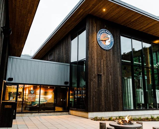 Exterior of Pelican Brewing Company in Lincoln City, OR, featuring a small fire pit on a paved patio.