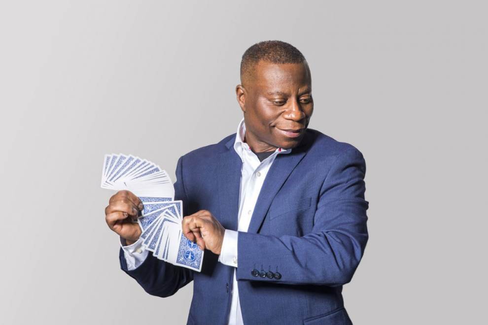 A magician in a blue blazer fans a deck of playing cards in promotion of the Festival of Illusions in Lincoln City, OR.