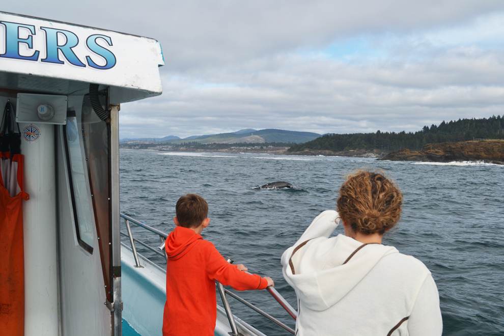 two kids watch as a whale pops out of the water from the deck of a Dockside Charter whale watching boat