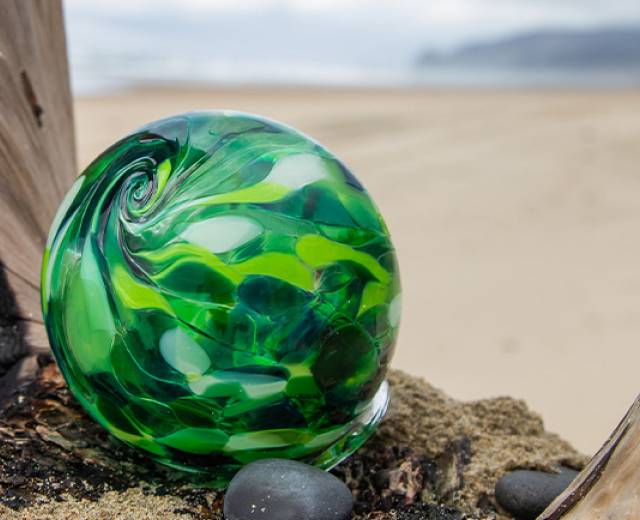 Finders Keepers glass float made with swirling green glass on a piece of driftwood in Lincoln City, OR