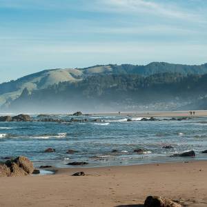 people walk along the water at the beach in Lincoln City, Oregon