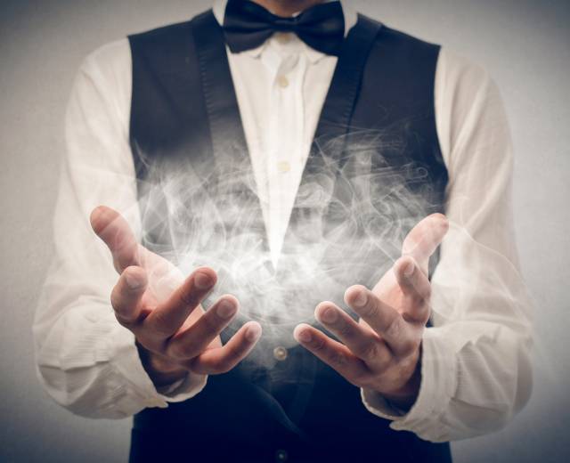 Smoke floats between a magicians hands