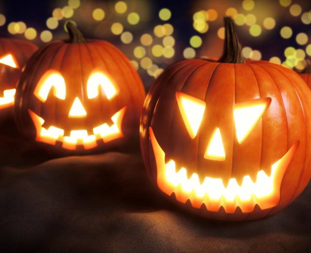 Four lit Halloween jack-o&#039;-lantern pumpkins in Lincoln City, Oregon