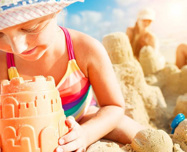 child builds a sandcastle with their family on the beach in Lincoln City, OR