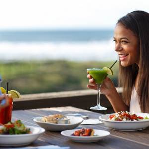 Two women enjoy food and drinks at a table outdoors at a Lincoln City restaurant
