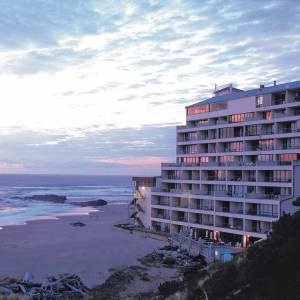The windows of a beachfront hotel in Lincoln City reflect a pink and purple sunset