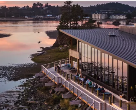 An aerial view of Pelican Brewing's patio area, overlooking Siletz Bay at sunset.